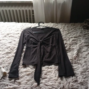 Svart långärmad knyt-topp Gina Tricot - Svart långärmad topp från Gina Tricot med v-ringning och snygg knytning framtill. Pris kan diskuteras
