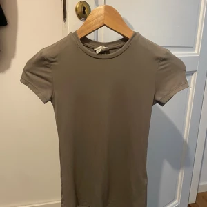 Beige kortärmad topp från H&M XS - Säljer en enkel och stilren beige topp från H&M i storlek XS. Modellen är kortärmad med rund hals och har en slim passform. Materialet är mjukt och stretchigt, perfekt för en clean och chill look. Passar dig som gillar minimalistisk stil. den är noppring, kan skicks bättre bilder vid intresse!