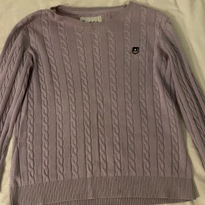 Ljuslila kabelstickad tröja Bondelid XS - Supersöt ljuslila kabelstickad tröja från Bondelid i storlek XS. Tröjan har rund hals, långa ärmar och ett litet broderat märke på bröstet. Perfekt för lager-på-lager och chill dagar. Klassisk och stilren vibe!