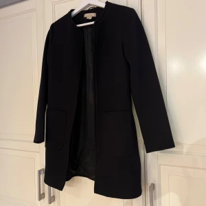 Svart kappa  - Stilren svart kappa från H&M i storlek 34.