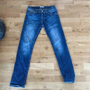 Blå jeans från Stone Island W31 - Säljer ett par snygga blå jeans från Stone Island med klassisk femficksdesign och ikonisk badge på bakfickan. Jeansen har raka ben, normal passform och coola slitningar framtill. Materialet är robust denim med tydliga kontrastsömmar. Vill du ha mer bilder bara hör av dig. 