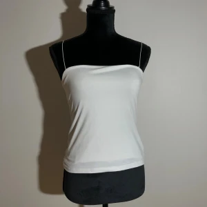 Vit linnetopp från Amisu - Säljer en stilren vit linnetopp från Amisu med tunna axelband. Längd ca 50cm. Pris: 10kr 