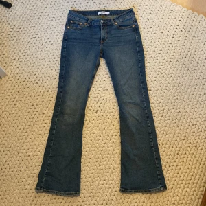 Blå bootcut jeans från Junkyard M - Snygga blå bootcut jeans med låg midja från Junkyard i klassisk denim. Jeansen har fem fickor, låg midja och utsvängda ben. Perfekt passform och coola kontrastsömmar. Materialet är stretchigt. Färgen är en djup blå nyans.