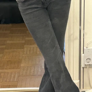 Mörkgrå bootcut jeans low waist - Snygga mörkgrå jeans med bootcut-modell och klassisk femficksdesign. Jeansen har en smal passform upptill och utsvängda ben, vilket ger en retro och trendig vibe. Tillverkade i mjukt denimtyg som sitter skönt hela dagen. 