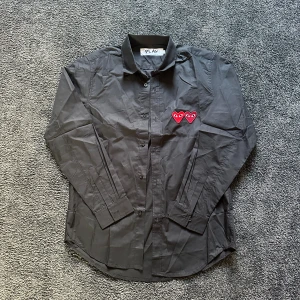 Cdg Skjorta Storlek L - Cdg skjorta stilren och fläckfri. Storlek L nyskick andvänd fåtal gånger. Kom mer frågor mm har alla bilder på mått osv. Mått 70 lång 41 bred 