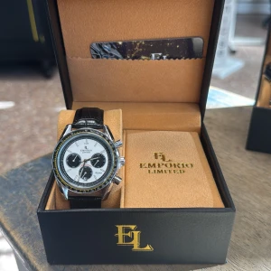 Emporio Limited kronografklocka svart/vit - Snygg kronografklocka från Emporio Limited med vit urtavla, svarta subdials och detaljer i gult. Boetten är i silverfärgad metall och armbandet är svart med krokopräglat mönster. Klockan levereras i exklusiv svart box med guldfärgad logga. Batteri
