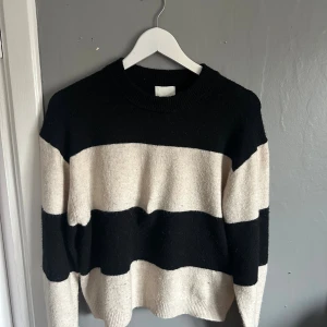 Randig svartvit stickad tröja H&M  - Säljer en stickad tröja från H&M i storlek XS med breda svarta och vita ränder. Tröjan har rund halsringning, långa ärmar och en klassisk, avslappnad passform. Perfekt för dig som gillar enkel men snygg stil.