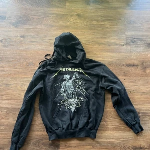 Metallica hoodie - Svart hoodie från Fruit of the Loom med Metallica '...And Justice For All'-tryck fram och bak. Klassisk huva med snörning och långa ärmar. Perfekt för dig som gillar bandmerch och vill ha en skön, avslappnad stil.