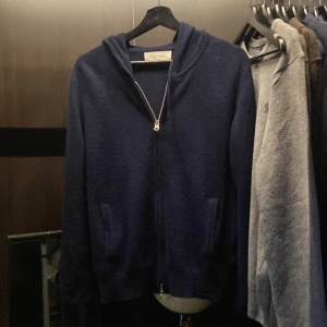 Mörkblå kashmirhoodie från Sayless - Mysig mörkblå hoodie från Sayless i lyxig kashmir. Tröjan har dragkedja framtill, huva och två fickor. Perfekt för dig som vill ha en stilren och bekväm look med exklusiv känsla. Passar nån runt 165-175, sitter mer som XS/liten S