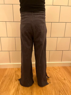 Mörkgrå wide linnebyxor med snörning - Snygga mörkgrå linnebyxor med breda ben och skön resår i midjan. Byxorna har snörning framtill och praktiska fickor på sidorna. Perfekta för en chill och avslappnad stil, med ett luftigt material som känns skönt mot huden.