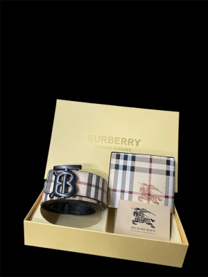 Rutig Burberry bälte med BB-spänne - Snyggt bälte från Burberry med klassiskt rutigt mönster i beige, svart, vitt och rött. Bältet har ett stort BB-spänne i mörk metall och är gjort i skinn. Perfekt accessoar för att lyfta din outfit med en lyxig touch.