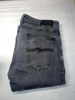 Nudie jeans  - Säljer ett par gråa skinny jeans från nudie jeans, modell skinny lin. Jeansen har smal passform och är tillverkade i stretchig bomull för extra komfort. Snygg tvätt med lite slitningar och detaljerade sömmar. Midja 40cm, längd 106cm. JAG SKICKAR EJ FLER BILDER NÄR JAG BÄR JEANSEN! för storleksguide hänvisar jag till måtten och för bättre inblick i passformen rekommenderar jag att googla på modellnamnet. kolla måtten noggrant :) s3