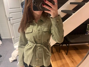 Grön skjortjacka med bälte - Säljer min ljusgröna overshirt/jacka från zalando. Den har knappar framtill, två bröstfickor och ett matchande bälte i midjan. Jackan är väl använd men i bra skick. Lite liten i storleken.