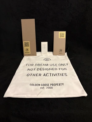 Golden Goose Super-Star sneakers, vit/blå - Golden Goose Super-Star sneakers i vitt skinn med ljusblå detaljer på hälen och grå mocka på bakkappan. Snygg platt sula i gummi med fiskbensmönster. Klassisk och clean design, tillverkad i Italien. Kommer med originalpåse och tillbehör.