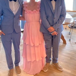 Ljusrosa långklänning med volanger - Säljer en drömmig ljusrosa långklänning med flera lager volanger och plisserat tyg. Från Nelly, perfekt till sommaren 