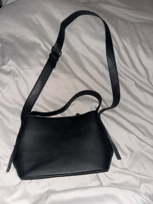 Svart axelväska i skinn - Hej! Jag säljer denna basic svarta väskan pågrund av jag inte fått någon användning av den, den är använd max 3 gånger och är därför i väldigt fint skick💕 skriv ifall du vill se fler bilder 