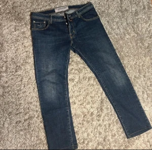 Jacob Cohën blå jeans style 622 - Snygga blå jeans från Jacob Cohën, modell style 622. Klassisk femficksdesign med kontrastsömmar och orange patch bak. Jeansen har slimpassform och är i storlek 33. Inga defekter 