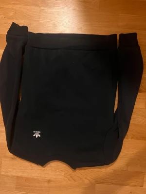 Svart Adidas sweatshirt - Svart långärmad sweatshirt från Adidas med klassisk logga i vitt framtill. Tröjan är tillverkad i mjuk fleece och har en enkel, clean design utan mönster eller detaljer. Perfekt för chill dagar eller när du vill ha en sportig look. Passar perfekt 160