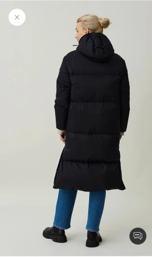 Svart lång pufferjacka med huva - Säljer en svart Lexintong lång pufferjacka  med huva och dragkedja hela vägen. Jackan har quiltad design, raka ärmar och sidofickor med dragkedja. Perfekt för kalla dagar när du vill vara både varm och stilren.