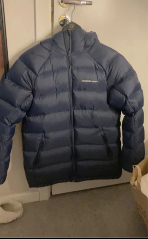 Mörkblå Peak Performance dunjacka - Säljer en snygg och varm mörkblå dunjacka från Peak Performance. Jackan har en praktisk huva och dragkedja framtill. !! bra skick!! Har aldrig använt och säljer eftersom den är för stor för mig så om du är intresserad skriv!!! Köpte runt 4500kr säljer 2399kr (priset kan diskuteras). Hjälp mig sälja den behöver köpa en ny jacka för det är vinter. Skriv privat för bilder