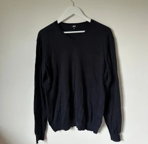 Svart v-ringad tröja från Uniqlo - Svart/mörkgrå v-ringad tröja från Uniqlo i en skön mix av linne och nylon. Tröjan har långärmade ärmar och ribbade muddar vid ärmslut och nederkant. Enkel och stilren design som funkar till många olika looks. 4Ö6