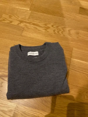 Mörkgrå merinotröja These Glory Days - Snygg mörkgrå stickad tröja från These Glory Days i mjuk och lyxig merinoull. Klassisk rund hals och långärmad modell som är perfekt för kyliga dagar. Enkel och stilren design som funkar till jeans eller chinos. Storlek M.