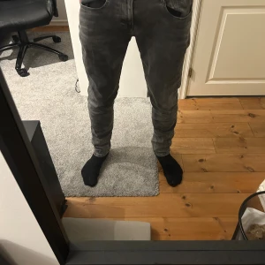 Replay Anbass grå jeans slim fit - Säljer ett par Replay Anbass jeans i grå tvättad färg. Modellen har slim fit med smalare ben och klassisk femficksdesign. Jeansen har normal midja och är tillverkade i stretchigt denim för skön passform. Perfekt för dig som gillar stilrena och moderna jeans.