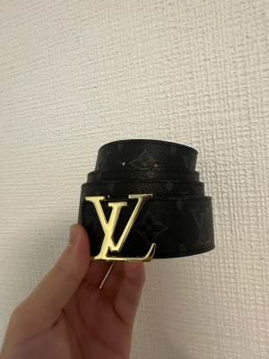 Svart bälte - Svart stilrent bälte med guldig badge i storlek 110