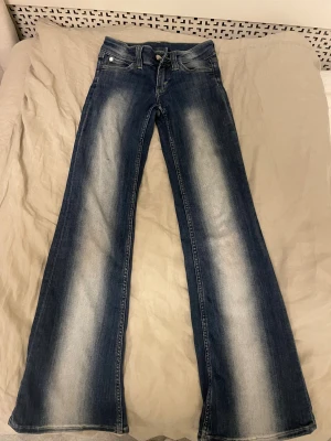 cheap Monday blå bootcut jeans - Snygga blå Weekday jeans med vitt i mitten.Storlek 24/30 och passar perfekt på någon som är runt 155 cm.Jättebra skick fast har en liten fläck på vänstra benet fast ingenting som märks.