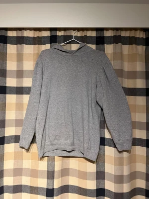 Grå hoodie från Oscar Jacobson - For sale: a stunning grey Oscar Jacobson hoodie made from 100% cashmere. Exceptionally soft, lightweight, and breathable – a true premium piece that works both for everyday wear and smarter occasions. The timeless grey color, perfect fit, and luxurious feel make this hoodie a wardrobe essential for years to come.