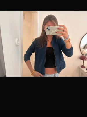 Blå bomberjacka i bomull - Snygg blå bomberjacka från Natural & Co i mjuk bomull. Jackan har dragkedja framtill, ribbade muddar och två fickor. Perfekt att slänga på sig över en crop top eller hoodie. Enkel och stilren design som funkar till det mesta.