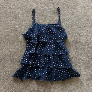 Mörkblå prickig volang-linnetopp - Supersöt mörkblå linne-topp med vita prickar och flera volanglager. Storlek XS/S