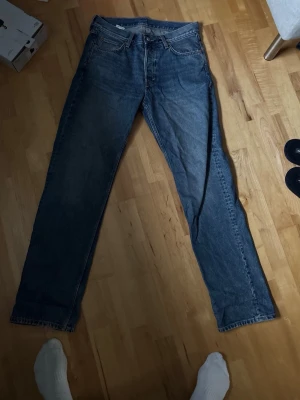 Blå Weekday jeans straight fit - Säljer ett par klassiska blå jeans från Weekday med rak passform och fem fickor. Jeansen har normal midja och är gjorda i slitstarkt denimtyg av bomull. Perfekta till sneakers eller boots och funkar året runt.