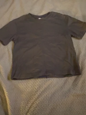 Mörkgrå basic t-shirt Gina Tricot - En enkel mörkgrå t-shirt från Gina Tricot, basically basics-kollektionen. Klassisk rund halsringning och korta ärmar. Perfekt till alla outfits där du vill ha en clean och stilren look.