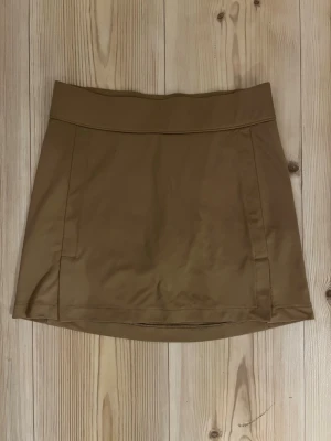 J.Lindeberg Amelie skirt - XS - Snygg beige kortkjol från J.Lindeberg i slät polyester. Kjolen har en enkel, stilren design med bred linning och diskret logga bak. Perfekt för dig som gillar sportig och clean stil.