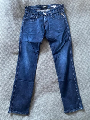 Mörkblåa Replay jeans - Hej! Säljer ett par mörkblå Replay Anbass slim fit jeans i storleken W29 och L30. Det är mycket bra skick och det finns inga hål eller fläckar på dom. De sitter ganska tajt så jag hade rekommenderat att vara där runt 170cm lång eller kortare. Hör av dig vid frågor eller funderingar!