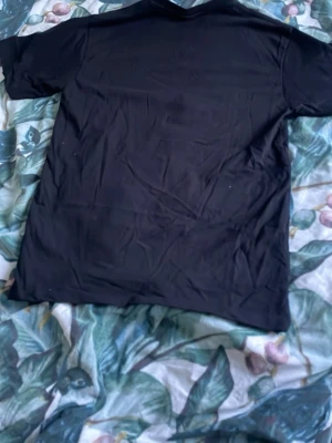 Svart t-shirt från Polo Ralph Lauren - Klassisk svart t-shirt från Polo Ralph Lauren med liten vit logga broderad på bröstet. T-shirten har rund hals och korta ärmar. Perfekt basic-plagg i mjuk bomull som funkar till allt.