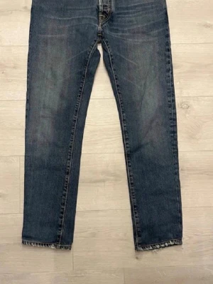 Jacob Cohen blå jeans med slitningar - Säljer ett par blå jeans från Jacob Cohen med snygga slitningar vid fickan och råa, fransiga benslut. Klassisk femficksmodell med normal passform och raka ben. Jeansen är tillverkade i mjukt denimtyg och har coola detaljer som kontrastsömmar.