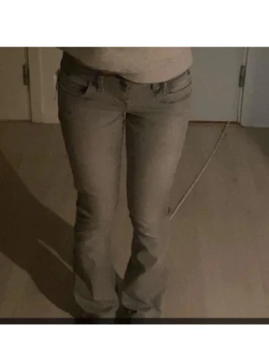 Grå bootcut jeans från Valerie - Snygga grå jeans från Valerie med bootcut passform och klassisk femficksdesign. Jeansen har låg midja och är tillverkade i ett mjukt bomullsmaterial med lite stretch för extra komfort. Perfekta för dig som gillar en stilren och enkel look.