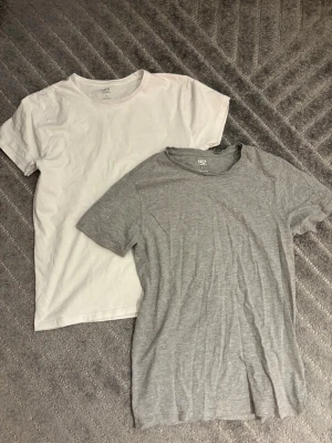 2-pack basic t-shirts från 157 - Två enkla och sköna t-shirts från 157, en i vitt och en i ljusgrått. Båda har rund hals och korta ärmar, perfekta till jeans eller shorts. Tillverkade i mjuk bomull för en avslappnad vibe.