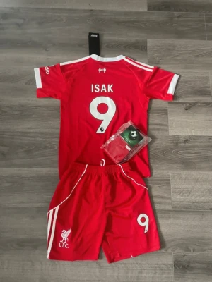 Liverpool Set Isak - Liverpool set med Isak. Helt nytt, inte ens testat! Lappen finns kvar! Shorts - storlek 24/140 Tröja - storlek 24 (antar 140 på den också) Nyaste stället säsong 25/26 Ej äkta
