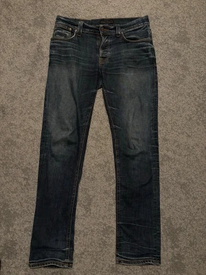 Nudie Jeans - Snygga Nudie Jeans i modellen Grim Tim. Storlek W33 L32 men sitter lite mindre i midjan. Extremt snygga slitningar och whiskers. Det är en liten lagning (se bild) Hör av er vid minsta fråga och pris kan diskuteras vid snabb affär 😊 