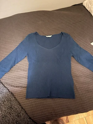 Mörkblå ribbad tröja från Cubus  - Säljer en mörkblå, ribbad långärmad tröja från Cubus i storlek XS. Tröjan har en djup v-ringning och är figurnära med stretchigt material. Perfekt till både jeans och kjol för en clean look.