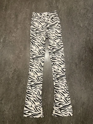 Zebramönstrade flare jeans Bershka - Säljer ett par riktigt snygga zebramönstrade flare jeans från Bershka i svart och vitt. Byxorna har klassisk femficksmodell och är tillverkade i ett stretchigt bomullsmaterial. ( lätt att sy pm ) Perfekta för dig som vill sticka ut med ikoniskt mönster. Säljer för att de tyvärr är för små för mig. 