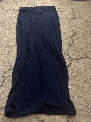 Mörkblå långkjol från 157 - Säljer en enkel och stilren mörkblå långkjol från 157. Kjolen har rak passform och är gjord i mjuk bomull som känns skön mot huden. Perfekt för dig som gillar minimalistisk stil och vill ha något bekvämt och snyggt i garderoben. Helt ny och aldrig använd.