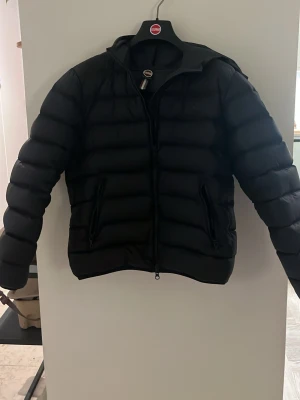 Svart pufferjacka från Colmar - Säljer en svart pufferjacka från Colmar med klassisk logga på ärmen. Jackan har en stilren design med horisontella sömmar, dragkedja framtill och två fickor med dragkedja. Perfekt för kalla dagar och riktigt skön att bära. Priset är inte fast i sten✌️👊