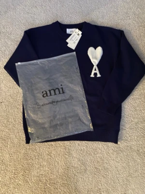 Mörkblå stickad tröja från Ami - Helt ny Snygg mörkblå stickad tröja från Ami Alexandre Mattiussi med deras ikoniska vita hjärta och A på bröstet. Tröjan har rund hals, långa ärmar och ribbade muddar. Perfekt för dig som vill ha en stilren och trendig look.pris går att diskutera ☺️