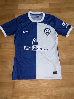 Nike Atlético Madrid 120-års jubileumströja - Säljer en limited edition Atlético Madrid 120-års jubileumströja från Nike. Tröjan är blå och vit med delad design, vita detaljer vid krage och ärmslut samt klubbmärke och sponsorer på bröstet. Tillverkad i lätt polyester med Dri-FIT-teknologi för bästa komfort.