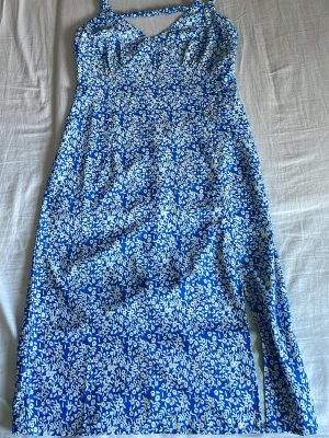 Sommarklänning!! - Söt blå sommarklänning med vita blommor och detaljer. Säljer då den inte kommer till användning. Vet tyvärr inte vilket märke det är. Postar inom 24 timmar!!💕