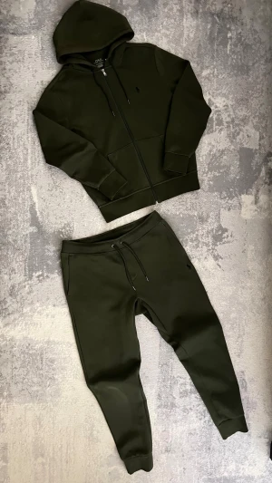 Mörkgröna mjukisbyxor och tröja från Polo Ralph Lauren - Snygga mörkgröna mjukisbyxor och tröja från Polo Ralph Lauren med. Byxorna är I storlek M och Tröjan i storlek S. tillverkade i mjukt bomullsmaterial.